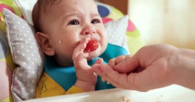 Anne bebeği kollarında tutuyor ve oğlunu kaşıkla besliyor. aile, yemek, çocuk, yeme ve ebeveynlik kavramı