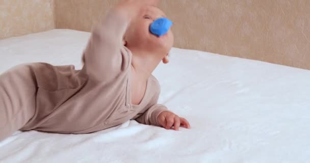 Criança, conceito de infância - close-up de sorrir feliz bebê brinca com um teether. Corte dos dentes. Os primeiros dentes. Joy toothless 7 meses bebê mordida, rói brinquedo teether — Vídeo de Stock