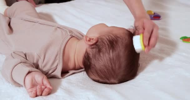 Matka czesająca malutkie włosy na głowie noworodka, gdy się budzi — Wideo stockowe