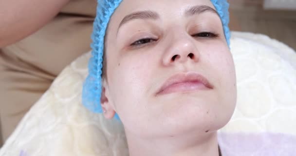 Kosmetolog nanáší peelingovou masku na ženskou tvář štětcem na kosmetické klinice. Kosmetička dělá proceduru péče o pleť. Lázeňská léčba v kosmetice — Stock video