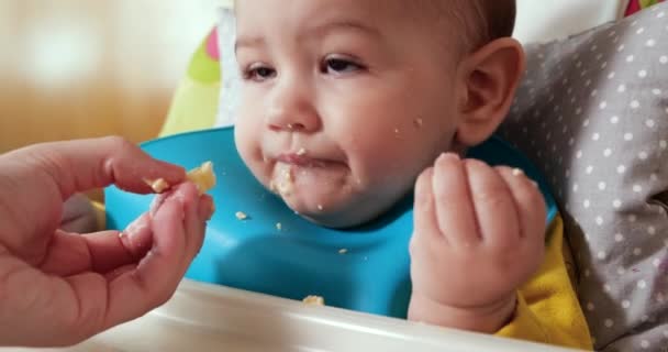 Moeder houdt de baby in haar armen en voedt haar zoon met een lepel. familie, voedsel, kind, eten en ouderschap concept — Stockvideo