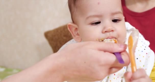 母親は赤ん坊を抱きかかえてスプーンで子供に食べさせる。家族、食べ物、子供、食事、親の概念 — ストック動画