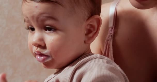 Retrato de un niño pequeño que se sienta en brazos de su madre. El niño feliz bebe leche o productos lácteos de una taza. Nutrición adecuada y natural para los niños — Vídeo de stock