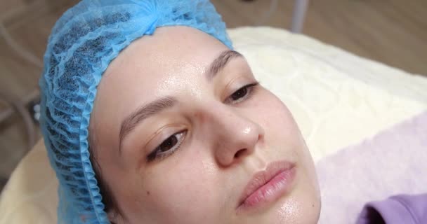 Mascarilla peeling facial, tratamientos de belleza spa, cuidado de la piel. Mujer miente y recibe tratamientos faciales por esteticista en el salón de spa, de cerca. Cuidado antienvejecimiento. Cosmetología y cuidado profesional de la piel — Vídeo de stock