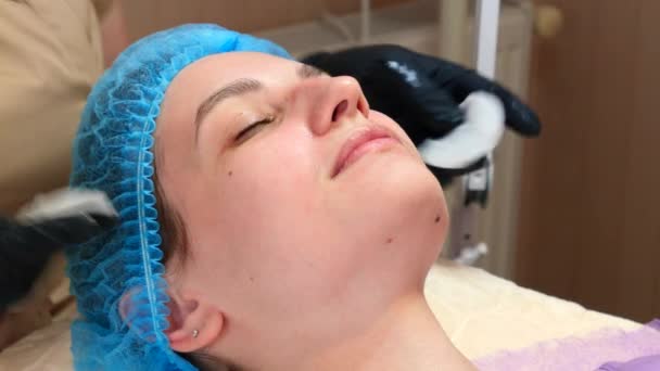 Lekarz kosmetolog wycierający twarz kobiety używa podkładek bawełnianych po zabiegu obierania. Lekarz robi zabieg kosmetyczny w klinice kosmetologii. Dbanie o skórę twarzy — Wideo stockowe