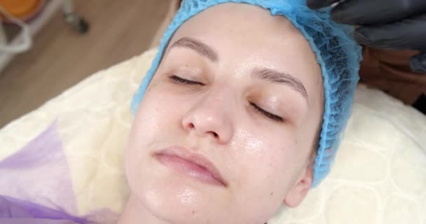 Cosmetólogo está aplicando mascarilla peeling en la cara de las mujeres usando cepillo en clínica de belleza. Esteticista haciendo el procedimiento de cuidado de la piel. Tratamiento de spa en cosmetología — Vídeo de stock