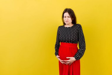 Karnı ağrıyan hamile bir kız renkli bir arka planda duruyor. izole.