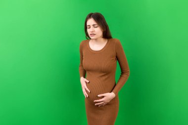 Karnı ağrıyan hamile bir kız renkli bir arka planda duruyor. izole.