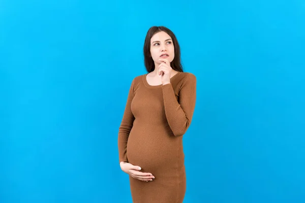Pensive pregnant woman choosing name for baby on colored background. Dream and Happy Pregnant Woman Thinking Imagining Motherhood Life. Copy Space.