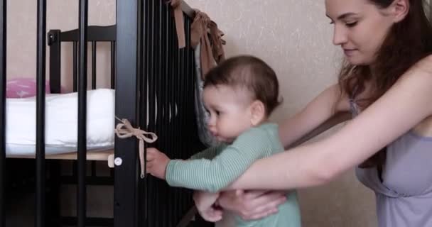 Mama hilft dem Kind, aufzustehen. Die ersten Schritte. Mutter lehrt das Kind aufzustehen — Stockvideo