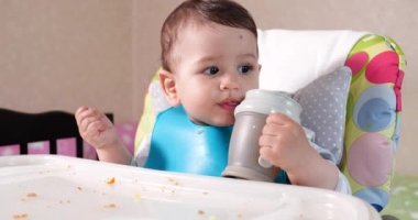 Anne çocuğu kaşıkla ve elle besler, aile yemeği ve ebeveynlik konseptiyle. İlk tamamlayıcı gıda ve kendini besleme.