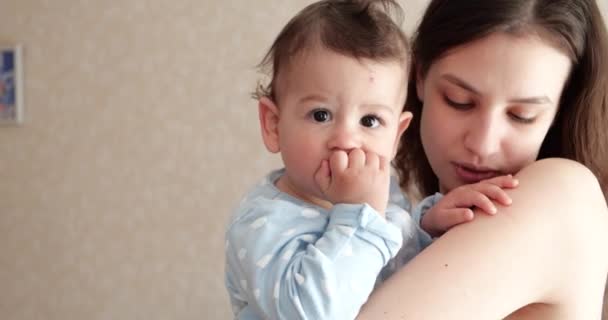 Mãe segura o bebê em seus braços e brinca com ele. Pouco bonito filho brinca com a mãe em casa — Vídeo de Stock