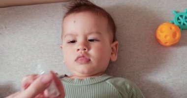 Yeni doğan çocuk burnuna ilaç damlatıyor. Bebek yedi aylık.