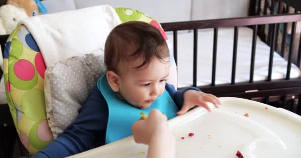 Mamá alimenta al niño con una cuchara y una mano, comida familiar y concepto de paternidad. primeros alimentos complementarios y autoalimentación — Vídeos de Stock