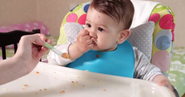 Mam voedt de jongen met een lepel en hand, familie eten en ouderschap concept. eerste aanvullende levensmiddelen en zelfvoeding — Stockvideo