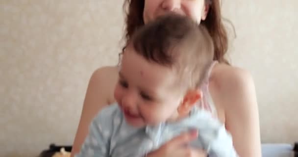 Mamma håller barnet i sina armar och leker med honom. Liten söt Son leker med mamma hemma — Stockvideo