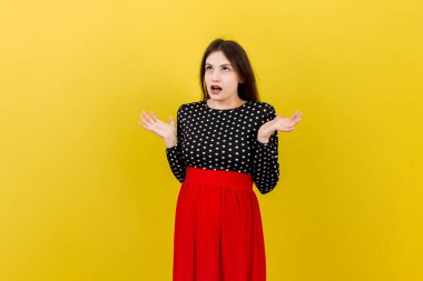 Mutlu ve şaşırmış hamile kadın renkli arka planda yalnız poz veriyor. Boşluğu kopyala.