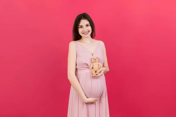 Счастливая Беременная Женщина Прижимает Плюшевого Мишку Животу Цветном Фоне Молодая — стоковое фото