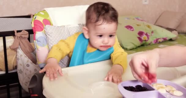 Mam voedt de jongen met een lepel en hand, familie eten en ouderschap concept. eerste aanvullende levensmiddelen en zelfvoeding — Stockvideo