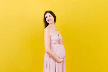 Mutlu hamile kadın renkli arka planda karnına dokunuyor. Müstakbel anne. Bir bebek bekliyorduk. Boşluğu kopyala.