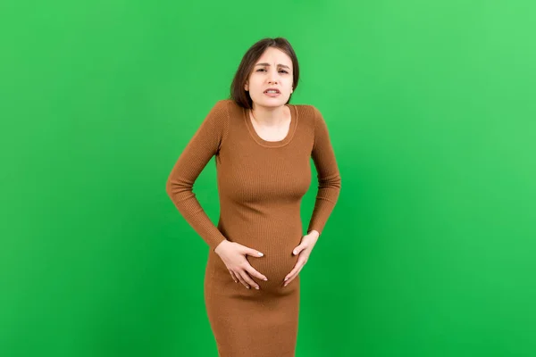 Μια Έγκυος Κοπέλα Που Έχει Στομαχόπονο Στέκεται Ένα Έγχρωμο Φόντο — Φωτογραφία Αρχείου