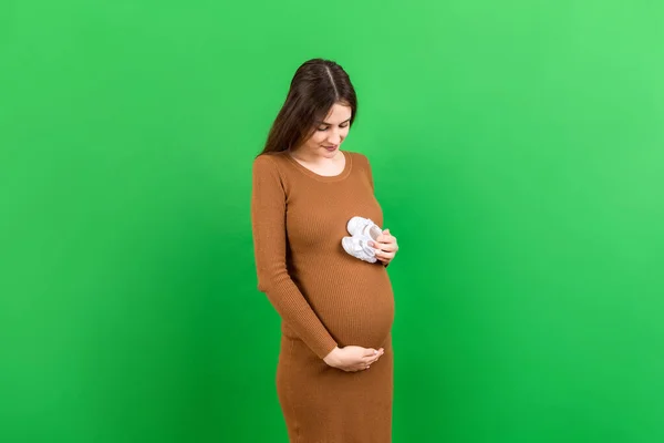Glückliche Schwangere Frau Mit Babystiefeln Vor Dem Bauch Vor Farbigem — Stockfoto