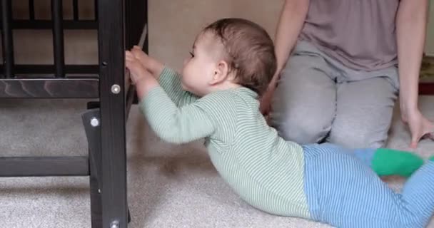 Mam helpt het kind om op te staan. De eerste stappen. Mam leert het kind op te staan. — Stockvideo