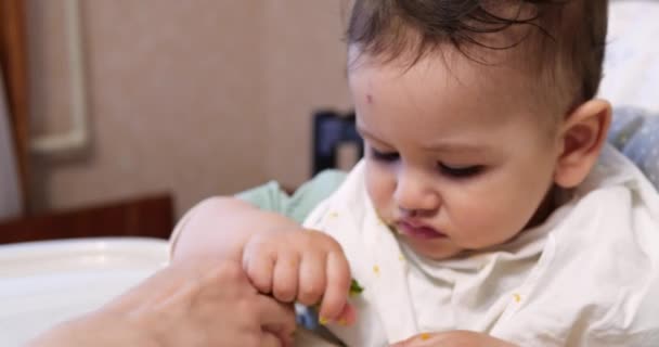 Mam voedt de jongen met een lepel en hand, familie eten en ouderschap concept. eerste aanvullende levensmiddelen en zelfvoeding — Stockvideo