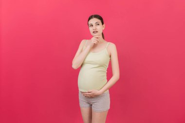 Düşünceli hamile kadın renkli arka planda bebek için isim seçiyor. Hayal Eden ve Mutlu Hamile Kadın Düşünen Annelik Hayatı. Boşluğu Kopyala.