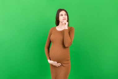 Düşünceli hamile kadın renkli arka planda bebek için isim seçiyor. Hayal Eden ve Mutlu Hamile Kadın Düşünen Annelik Hayatı. Boşluğu Kopyala.