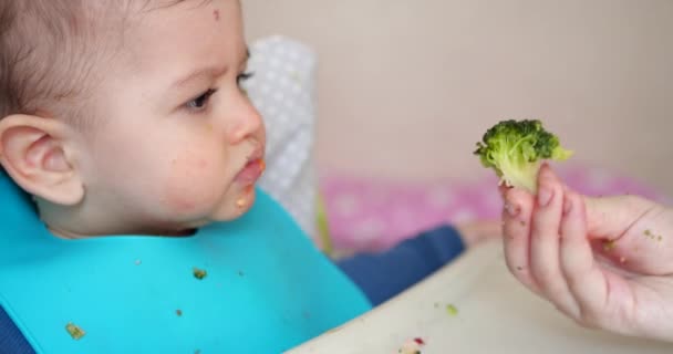 Mamãe alimenta o menino com uma colher e mão, comida familiar e conceito de paternidade. primeiros alimentos complementares e auto-alimentação — Vídeo de Stock