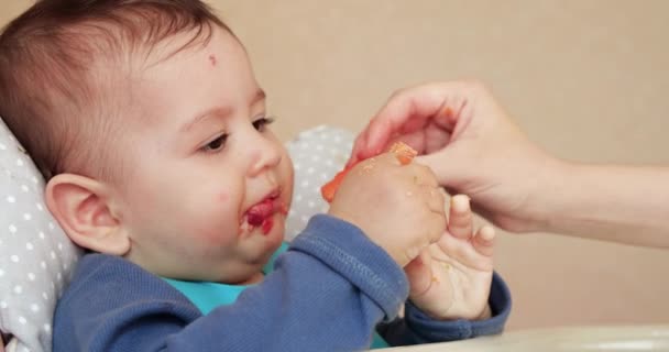 Mama karmi chłopca łyżką i ręką, rodzinnym jedzeniem i koncepcją rodzicielstwa. pierwsza żywność uzupełniająca i samokarmienie — Wideo stockowe