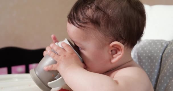 Милый мальчик, пьющий стакан воды дома. Крупный план. Ребенок пьет воду из пластиковой кружки — стоковое видео
