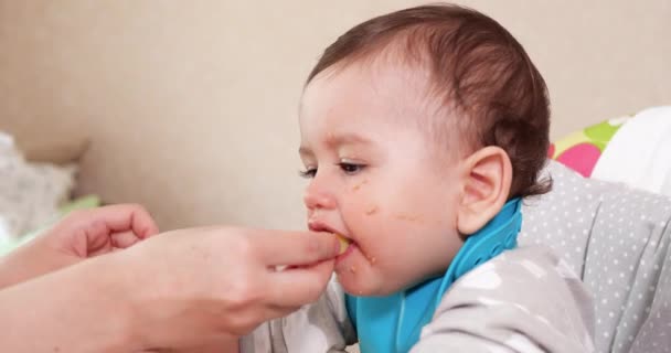 Mamá alimenta al niño con una cuchara y una mano, comida familiar y concepto de paternidad. primeros alimentos complementarios y autoalimentación — Vídeos de Stock