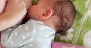 Anne, bebeği evde emziriyor. Annelik ve annelik konsepti. Neşeli anne emzirmeyi sever.