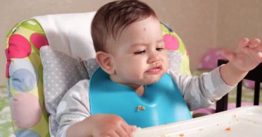 Anne çocuğu kaşıkla ve elle besler, aile yemeği ve ebeveynlik konseptiyle. İlk tamamlayıcı gıda ve kendini besleme.