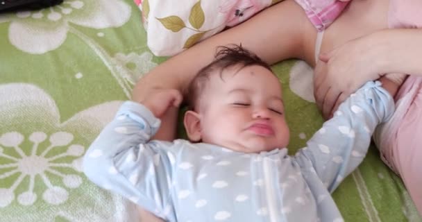 Маленький мальчик растягивается в постели после пробуждения, ребенок тянется после сна и мама начинает грудное вскармливание — стоковое видео