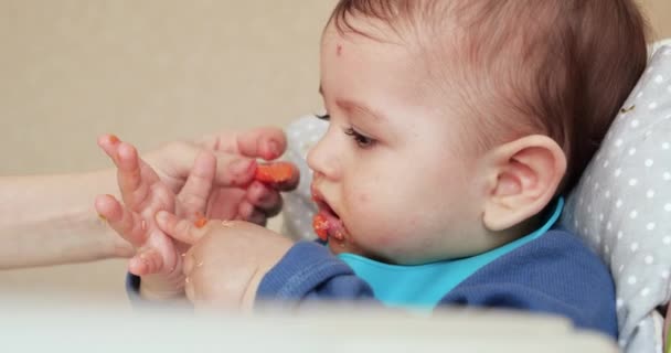 La mamma nutre il ragazzo con un cucchiaio e una mano, cibo di famiglia e concetto di genitorialità. primi alimenti complementari e autoalimentazione — Video Stock