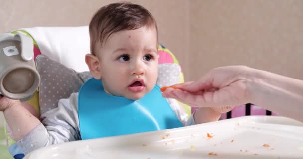 La mamma nutre il ragazzo con un cucchiaio e una mano, cibo di famiglia e concetto di genitorialità. primi alimenti complementari e autoalimentazione — Video Stock