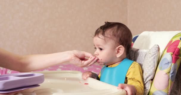 Мама кормит мальчика ложкой и рукой, семейным питанием и воспитанием. первая дополнительная пища и самокормление — стоковое видео