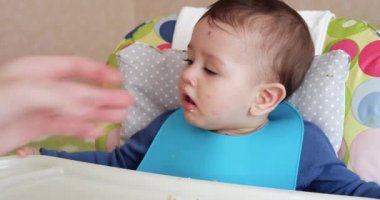 Anne çocuğu kaşıkla ve elle besler, aile yemeği ve ebeveynlik konseptiyle. İlk tamamlayıcı gıda ve kendini besleme.