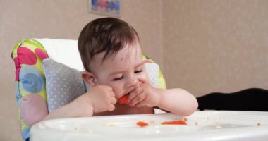 Anne çocuğu kaşıkla ve elle besler, aile yemeği ve ebeveynlik konseptiyle. İlk tamamlayıcı gıda ve kendini besleme.