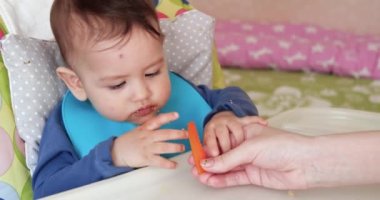 Anne çocuğu kaşıkla ve elle besler, aile yemeği ve ebeveynlik konseptiyle. İlk tamamlayıcı gıda ve kendini besleme.