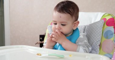 Anne çocuğu kaşıkla ve elle besler, aile yemeği ve ebeveynlik konseptiyle. İlk tamamlayıcı gıda ve kendini besleme.