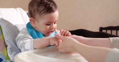 Anne çocuğu kaşıkla ve elle besler, aile yemeği ve ebeveynlik konseptiyle. İlk tamamlayıcı gıda ve kendini besleme.