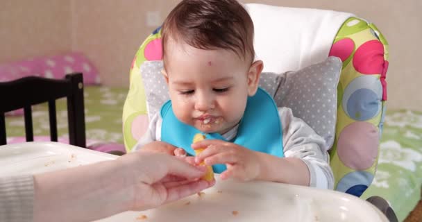 Mom feeds the boy with a spoon and hand, family food and parenthood concept. first complementary foods and self-feeding — Stock Video