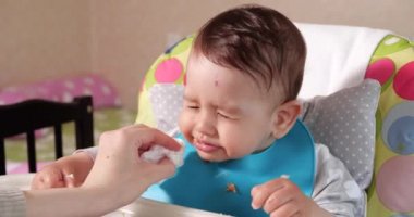 Anne çocuğu kaşıkla ve elle besler, aile yemeği ve ebeveynlik konseptiyle. İlk tamamlayıcı gıda ve kendini besleme.