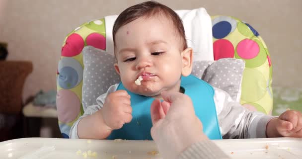 La mamma nutre il ragazzo con un cucchiaio e una mano, cibo di famiglia e concetto di genitorialità. primi alimenti complementari e autoalimentazione — Video Stock