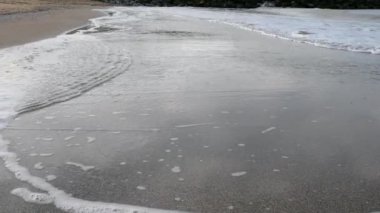 Kumsalda kumları ve dalgaları kapatıyoruz. Seyahat yaz konsepti. Plajda tatil. Sonbahar günündeki sahilin manzarası. Dalga