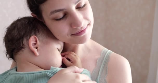 Madre sostiene a su hijo dormido en casa y lo mece. niño durmiendo en sus brazos madre — Vídeo de stock
